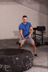 Image showing man workout with hammer and tractor tire