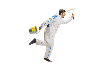 Image showing Young male decorator painting with a paint roller climbed a ladder isolated on white background.