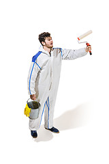 Image showing Young male decorator painting with a paint roller climbed a ladder isolated on white background.