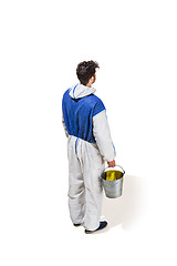 Image showing Young male decorator painting with a paint roller climbed a ladder isolated on white background.