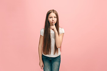 Image showing The young teen girl whispering a secret behind her hand over pink background