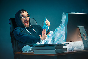 Image showing Young stressed handsome businessman working at desk in modern office shouting at laptop screen and being angry about spam