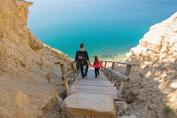 Image showing Dad and daughter go down the steep mountain stairs to the sea