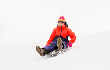 Image showing girl sliding down on snow saucer sled in winter