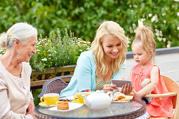 Image showing happy family with smartphone at cafe terrace