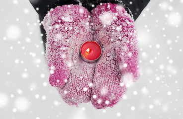 Image showing close up of hands in winter mittens holding candle