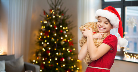 Image showing girl in santa hat with teddy bear on christmas