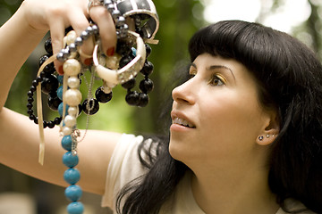 Image showing brunette holding a lot of beads