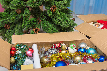 Image showing Christmas tree decorations in a box in front of an artificial Christmas tree