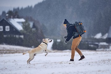 Image showing Man playing with dog in winter landscape