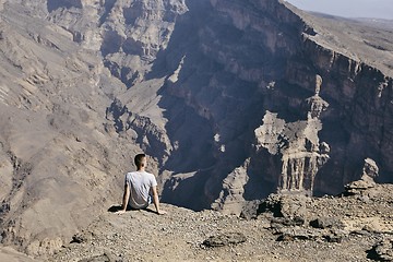 Image showing Tourist resting on the edge of cliff