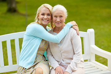 Image showing daughter with senior mother hugging on park bench