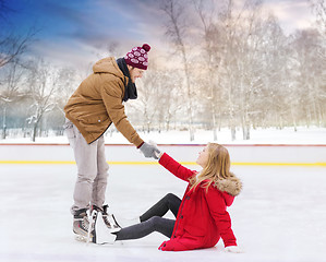 Image showing man helping woman to get up from skating rink