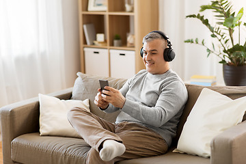 Image showing man with smartphone and headphones at home