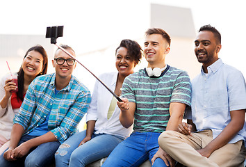 Image showing friends taking picture by on selfie stick in city