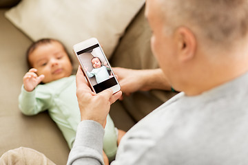 Image showing father photographing baby by smartphone