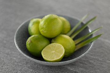 Image showing close up of limes in bowl on slate table top