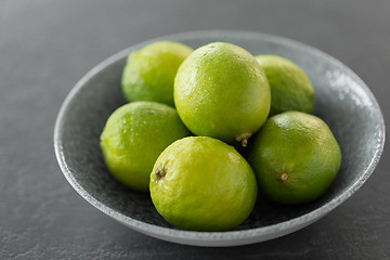 Image showing close up of whole limes in bowl on slate table top