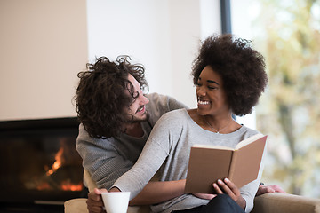 Image showing multiethnic couple hugging in front of fireplace