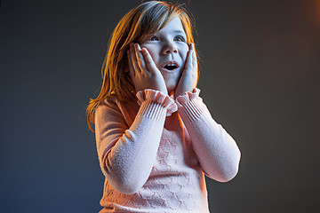 Image showing The young attractive teen girl looking suprised isolated on dark blue