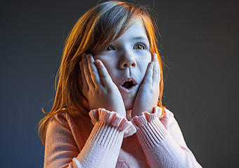 Image showing The young attractive teen girl looking suprised isolated on dark blue