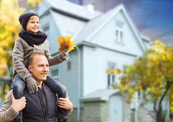 Image showing father and son with autumn maple leaves over house
