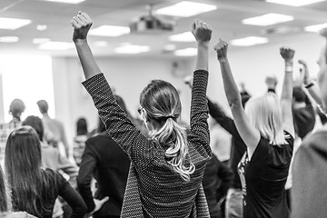 Image showing Participants of interactive motivational speech feeling empowered and motivated, hands raised high in the air.