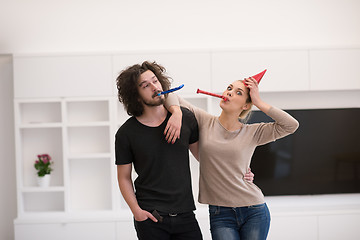 Image showing couple in party hats blowing in whistle