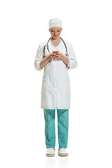 Image showing Beautiful young woman in white coat posing at studio. Full length studio shot isolated on white.