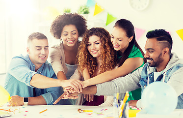 Image showing happy team at office party holding hands together