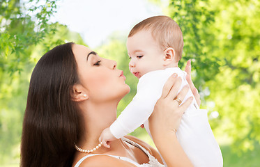 Image showing mother kissing baby over green natural background