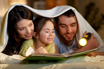 Image showing happy family reading book in bed at night at home