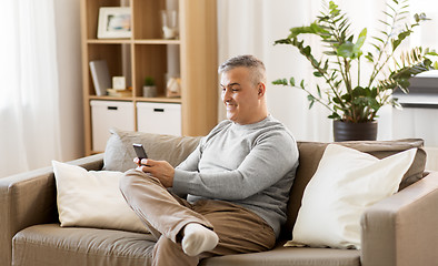 Image showing man with smartphone sitting on sofa at home