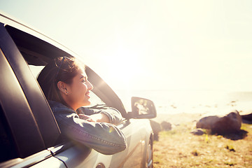 Image showing happy teenage girl or young woman in car