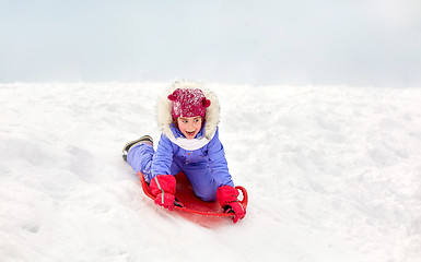 Image showing girl sliding down on snow saucer sled in winter