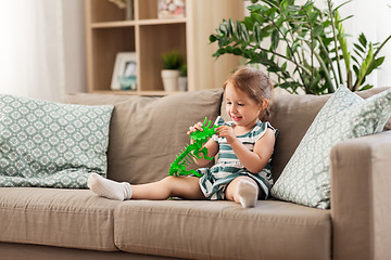 Image showing happy baby girl playing with toy dinosaur at home