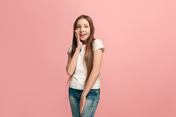 Image showing The young teen girl whispering a secret behind her hand over pink background