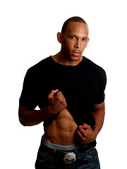 Image showing Young black man holding up shirt in jeans