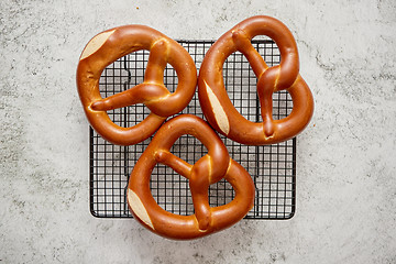 Image showing Three german fresh baked pretzel buns placed on steel grill frame