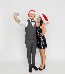 Image showing couple in santa hats aking selfie at christmas