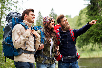 Image showing happy friends or travelers with backpacks hiking