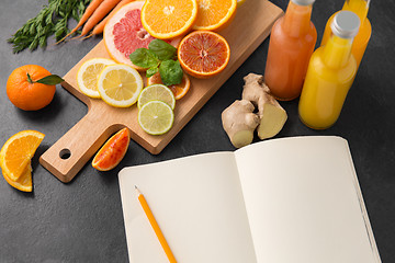 Image showing close up of fruits, juices and notebook on table