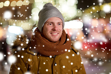 Image showing happy young man over christmas lights in winter