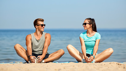 Image showing smiling couple stretching legs on beach