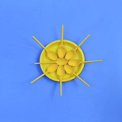 Image showing A yellow plastic plate and spoons lay around it on a bright blue background. The concept of a holiday, picnic.