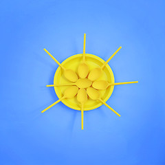 Image showing A yellow plastic plate and spoons lay around it on a bright blue background. The concept of a holiday, picnic.