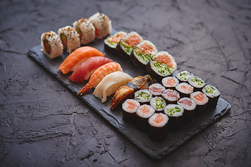 Image showing Sushi rolls set with salmon and tuna fish served on black stone board