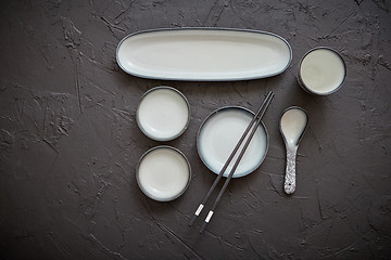 Image showing Set of empty ceramic dishes for sushi and rolls on a black stone table