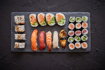 Image showing Sushi rolls set with salmon and tuna fish served on black stone board