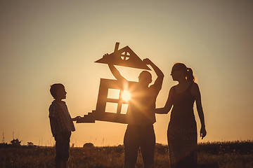 Image showing Happy family standing on the field at the sunset time.